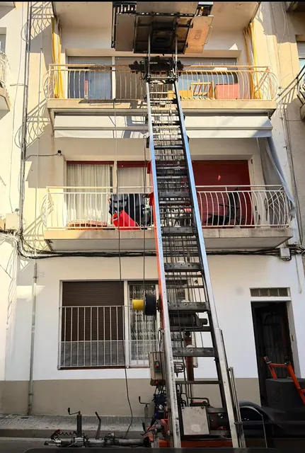 Plataforma elevadora lliurant mobles pel balcó d'un segon pis a Calella