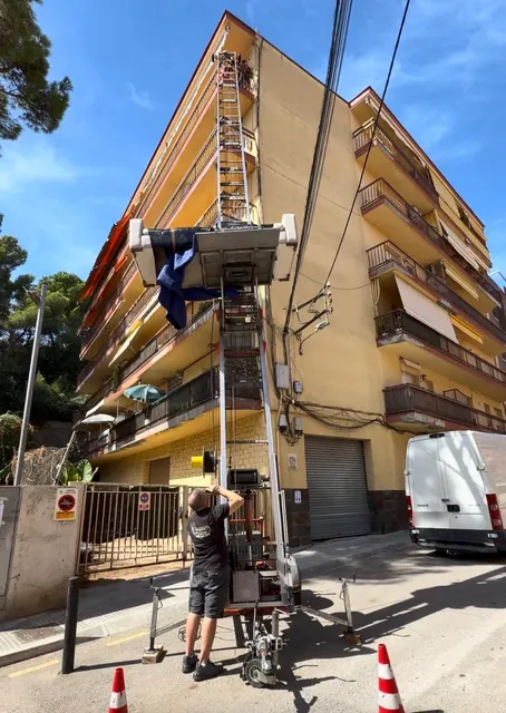 Plataforma elevadora pujant un sofà per la façana d'un edifici de cinc plantes a Canet de Mar